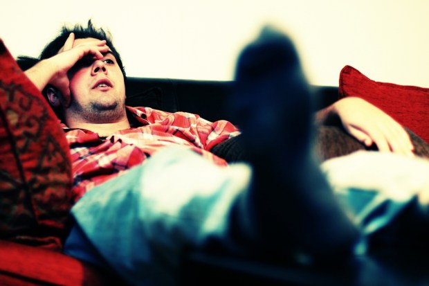 Lazy man chilling out on sofa watching tv