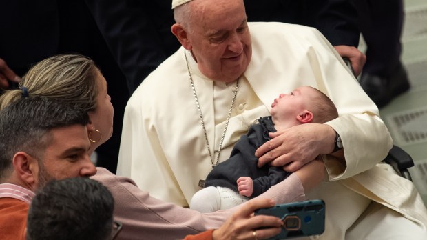 Pope Francis holds a baby at the end of his weekly general audience