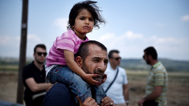 A Syrian man carries his daughter, as refugees abandon the makeshift camp of Idomeni in northern Greece