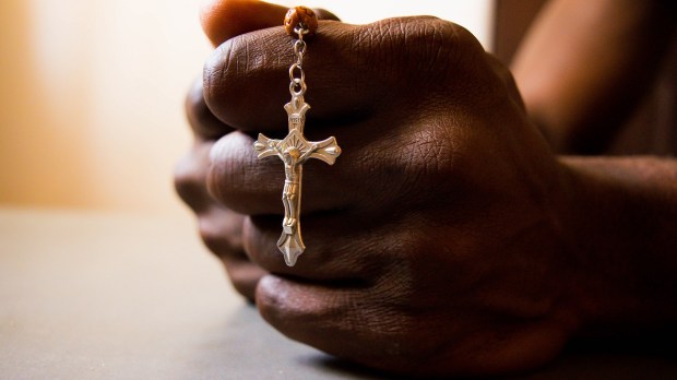 Nigerian man prays, hands, rosary