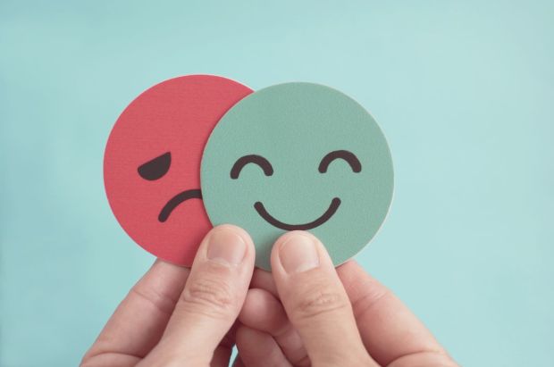 Manos-con-cara-triste-escondiendose-detras-de-cara-feliz