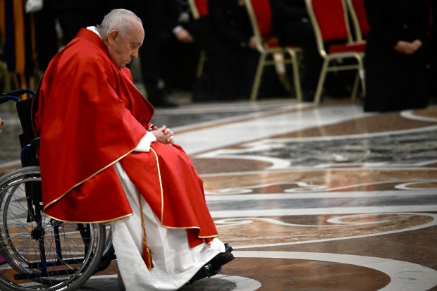 Pope Francis prays as he arrives to preside the Passion of the Lord mass on Good Friday as part of the Holy Week celebrations, at St Peter's Basilica in the Vatican on March 29, 2024