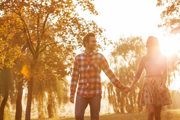 Young couple in love walking in the autumn park holding hands