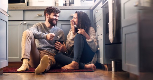 Shot of a happy young couple sharing a tub of ice cream in their kitchen at home